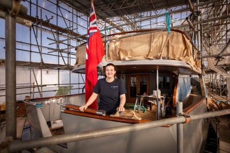 A woman stands on the deck of a yacht attached to scaffolding