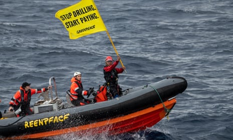 Greenpeace activist Yeb Saño seen in a motor dinghy waving a flag saying 'stop drilling - start paying'
