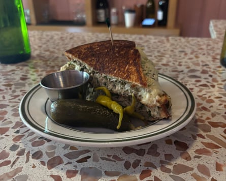 A wedge-shaped sandwich with dill pickle and melted cheese