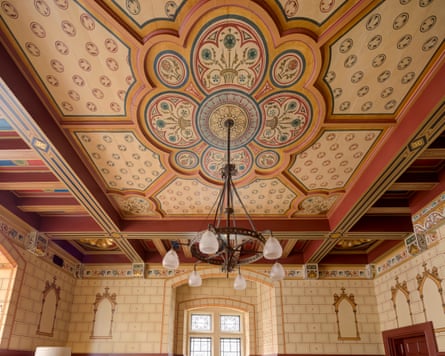 An ornate ceiling with a painted centrepiece and a chandelier