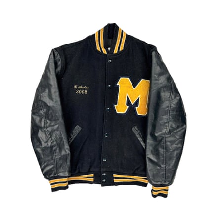 A black leather varsity jacket with an embroidered yellow M detail and yellow trim on the collar, cuffs and bottom