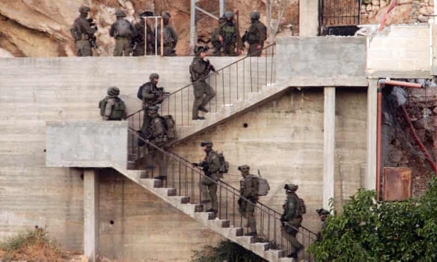 Israeli soldiers deploy near a Palestinian house