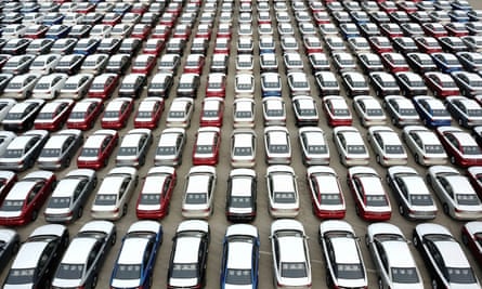An aerial view of an endless grid of cars, parked neatly in rows and columns.