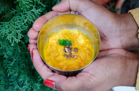 Hands hold a small bowl of carrot pudding