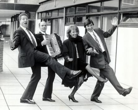 A black and white picture of Esther Rantzen and other cast members standing in a line, with one playing an accordion and the others raising their legs in the air