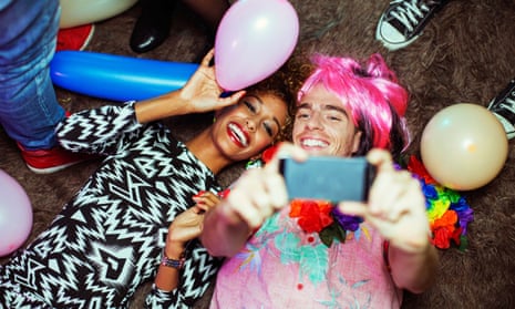Couple taking self-portrait with cell phone on floor at party