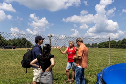 four people chatting by fence next to field