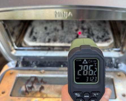 Closeup image of an IR thermometer taking the temperature reading of an outdoors pizza oven.