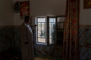Abdul Walid Abdul, 50, stares out the window of his house in Al Musharrah