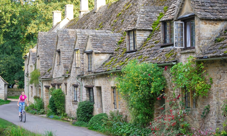Cycling by stone cottages in Bibury, Gloucestershire