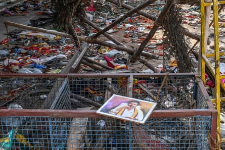 A portrait of Vijay lies on a metal railing amid scattered shoes and clothes