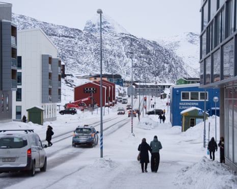 People walk along a snow-covered street in Nuuk city, Greenland