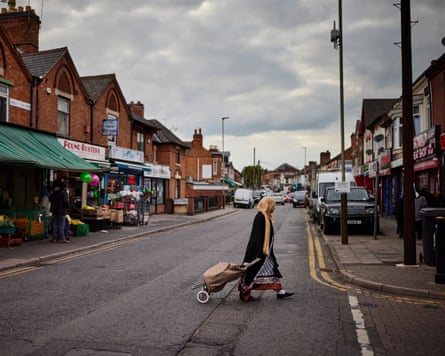 A woman with a shopping trolley crosses Green Lane Road