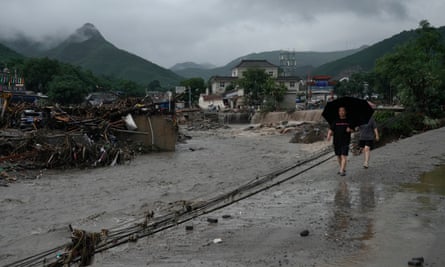 People walk by a damaged riverbank in Beijing’s Mentougou district, where flooding has caused severe damage.