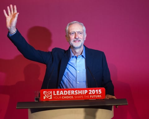 Jeremy Corbyn at the podium with one hand raised in the air.