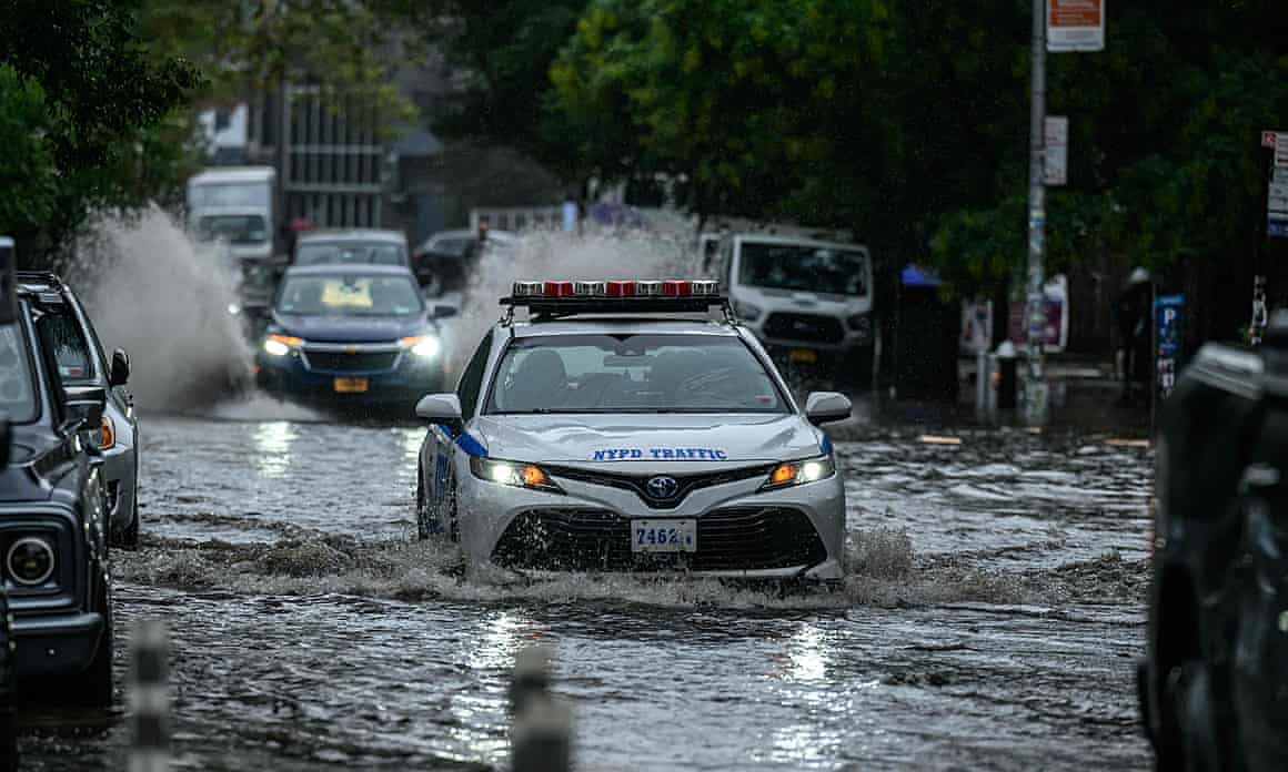 An NYPD car drives down a flooded street, the water up past its tires, in Brooklyn, New York on September 29, 2023.