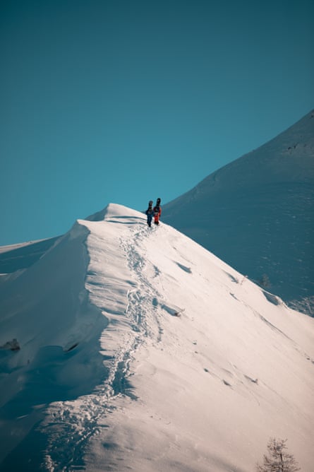 Dua snowboarder petualang mendaki menuju zona pendaratan mereka. Back country Verbier, Swiss.