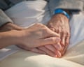 Nurse holding an elderly man's hand