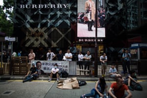 Demonstrators and bystanders gather in front of a Burberry Group Plc store on Canton Road in the area of Tsim Sha Tsui in Hong Kong, China.