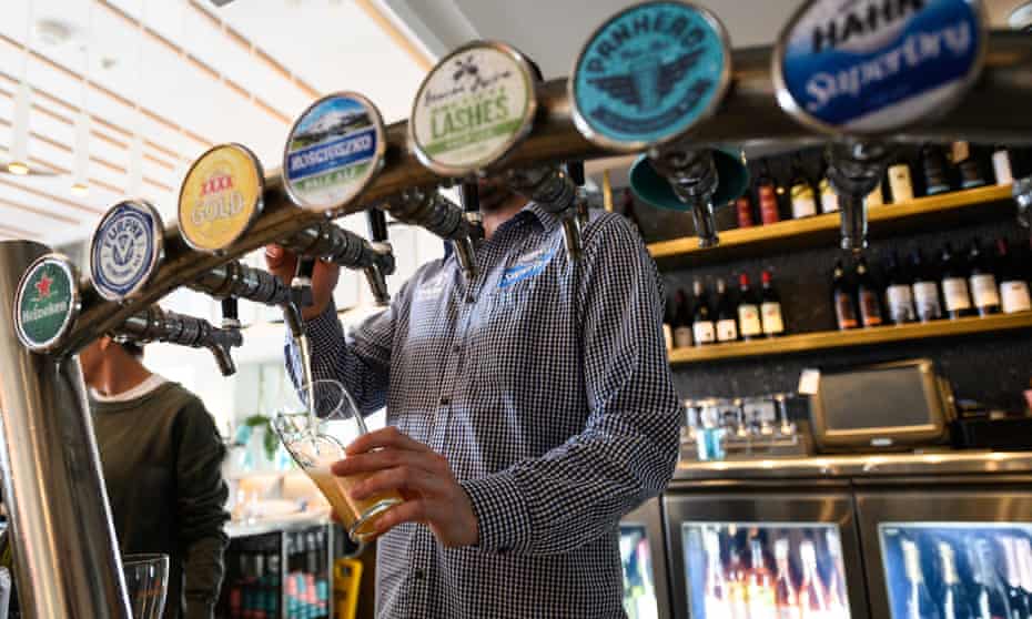 A hospitality worker pours a beer