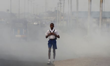 A school boy walks past smoke and fumes emitted from a dump in Port Harcourt.
