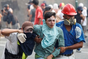 An injured demonstrator is assisted by others in Caracas.