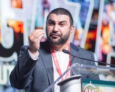 man in suit speaks at lectern with hand gestured