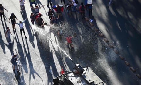 Riot police fire a water cannon to disperse demonstrators at La Alameda in Santiago on Monday.