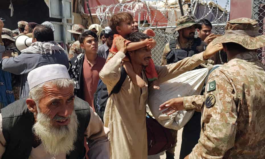 Pakistani soldiers check stranded Afghan nationals at a Pakistan-Afghanistan border crossing in August.