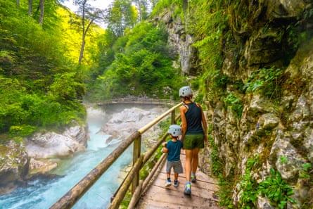 Mother and son walking on a boardwalk in a gorge next to fast flowing stream