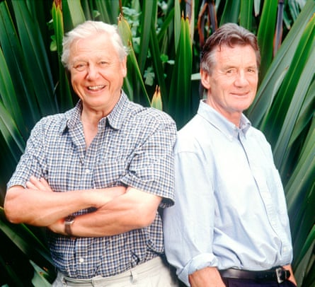 David Attenborough and presenter Michael Palin standing back to back, large green leaves behind them, in 2002