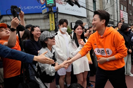 Lee Jun-seok, the presidential candidate of the New Reform Party, right, shakes hands with a woman during a presidential election campaign in Seoul, South Korea, Saturday, May 17, 2025.