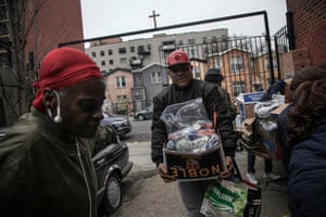 Surrounded by a few volunteers, a man carries food donations from St. Stephen Outreach in the Brooklyn borough of New York, on Friday, March 20, 2020. For decades, American nonprofits have relied on a cadre of volunteers who quite suddenly aren’t able to show up. With millions staying home during the pandemic, charities that help the country’s neediest are facing even greater need.