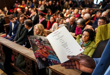 Mourners behind a hand holding the order of service
