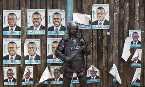 A Ugandan police officer stands outside an opposition party headquarters.