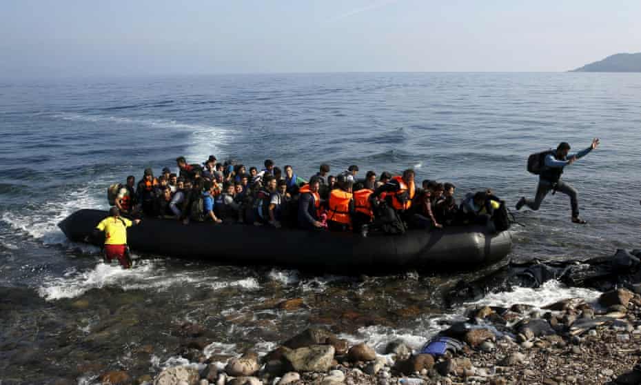 Migrants arrive on a raft on to a beach on the Greek island of Lesbos.