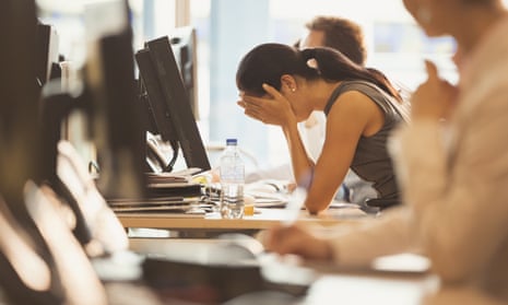 Stressed woman with head in hands at office desk