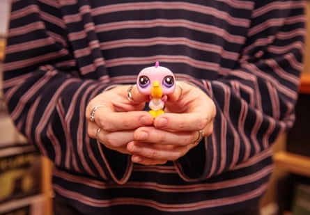 Hands holding a tiny pink toy bird