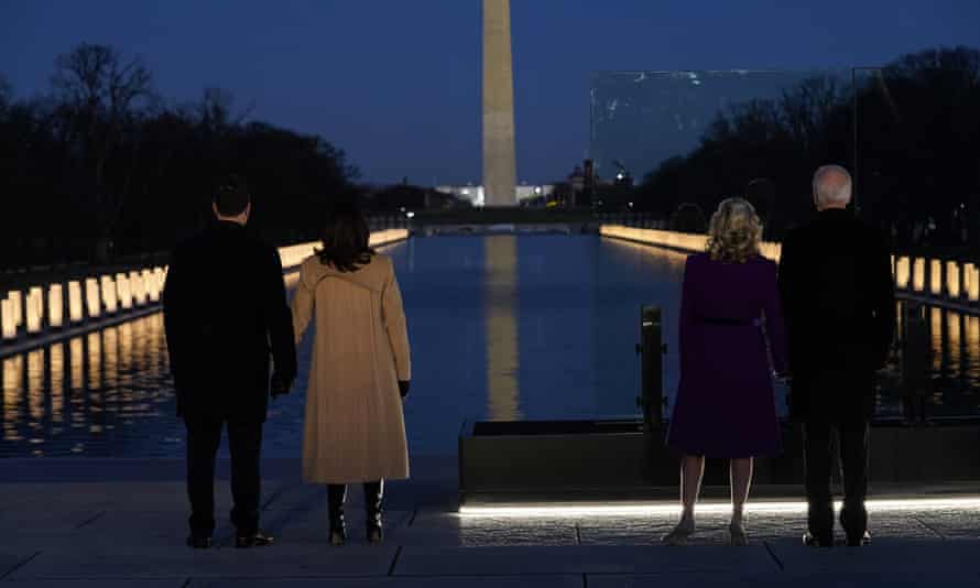 With the Washington Monument in the background, President-elect Joe Biden stands with his wife Jill Biden and Vice President-elect Kamala Harris stands with her husband Doug Emhoff as they look at lights placed around the Lincoln Memorial Reflecting Pool during a Covid-19 memorial Tuesday, January 19, 2021, in Washington.