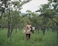 A person stands topless in a grassy woodland wearing a sculptural bull costume around their waist a photograph by Marisol Mendez, Bull 2019.