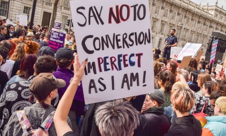 A protester holds a 'Say No To Conversion' sign and other trans rights protesters