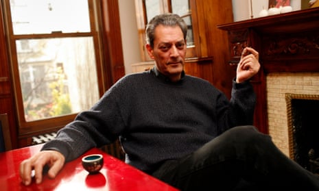 Paul Auster sitting at a red table