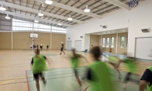 Schoolchildren exercise in an indoor sports hall. 