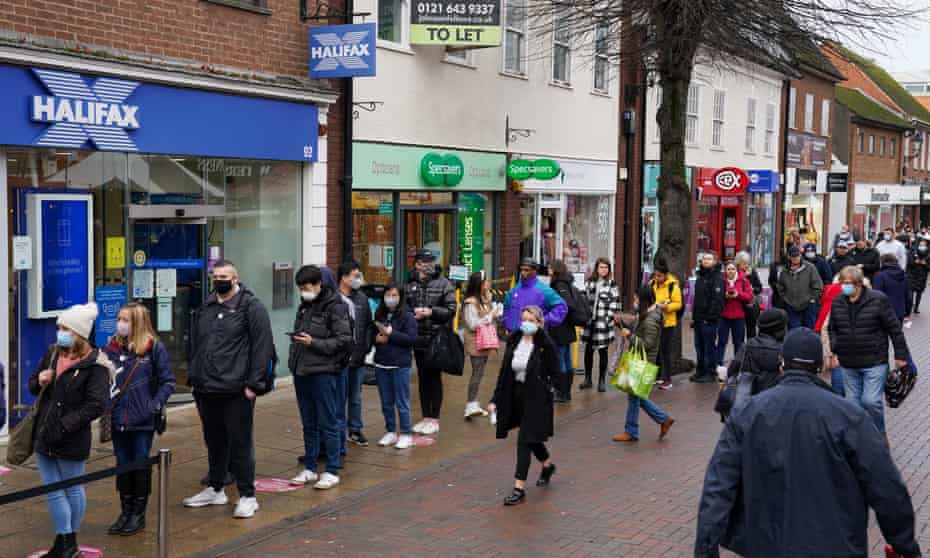People in Solihull High Street, West Midlands, queue for Covid booster shots.