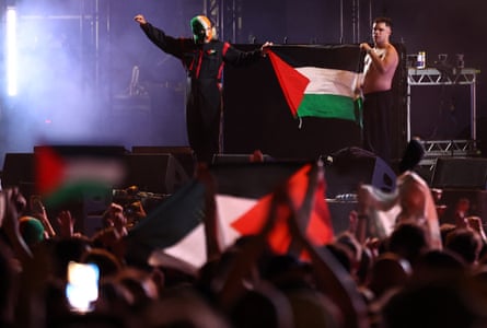 Kneecap’s Naoise O Caireallain, right, and JJ O’Dochartaigh hold up a Palestinian flag on stage.