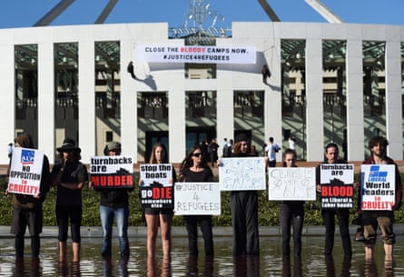 Pro-refugee protesters stand in the fountain in front of Parliament House as fellow protesters abseil down the edifice of Parliament House to hang a banner opposing Australia’s offshore detention of asylum seekers.