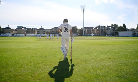 Cook walks out to bat on a sunny day
