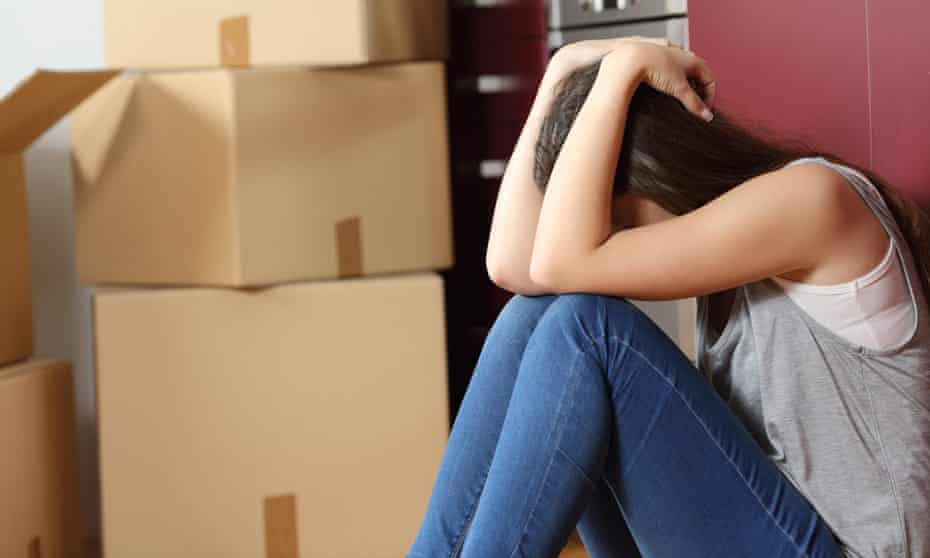 Sad woman sitting on the floor in the kitchen next to moving boxes