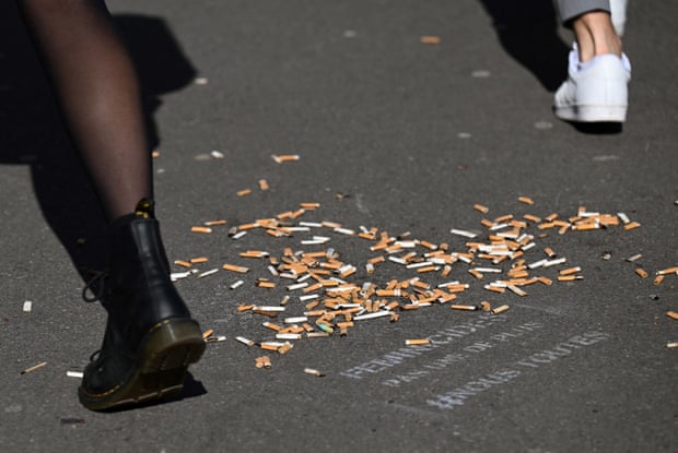 A pavement littered with a pile of cigarette butts
