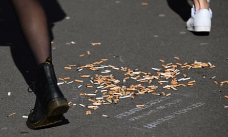 People step past cigarette butts littering a pavement in Paris